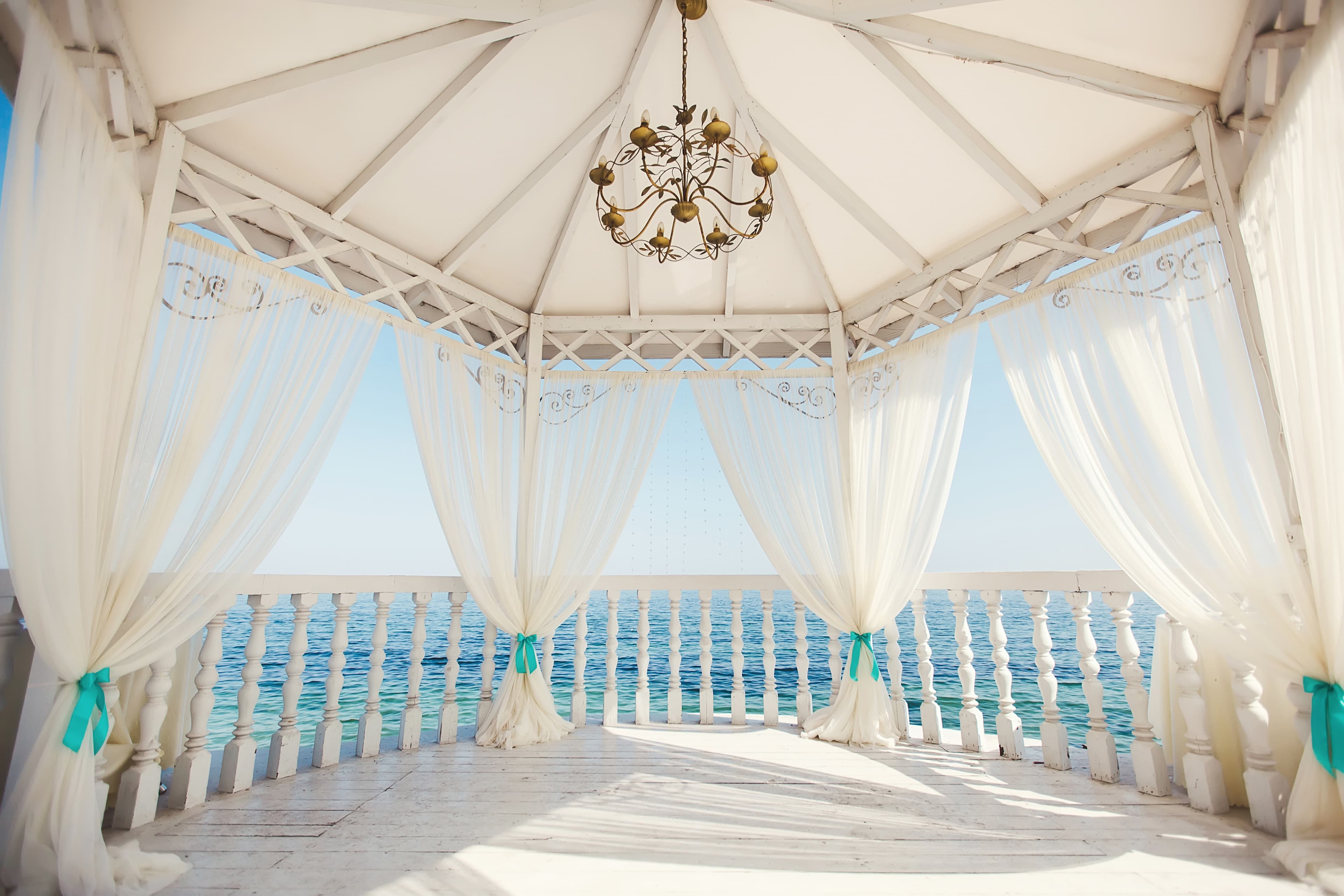 Pareja de recién casados abrazándose bajo un arco de flores en una boda en la playa, con el mar de fondo.